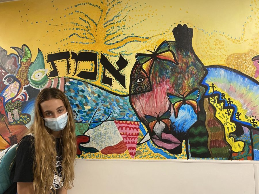  “The mural outside the art room gives off a feeling of comfort and friendliness to the incoming students and faculty,” says Prowler photographer and Staff Writer Carly Plotkin. Sophomore Eliana H. shows off the work of art created by former dTHS and exchange students. 