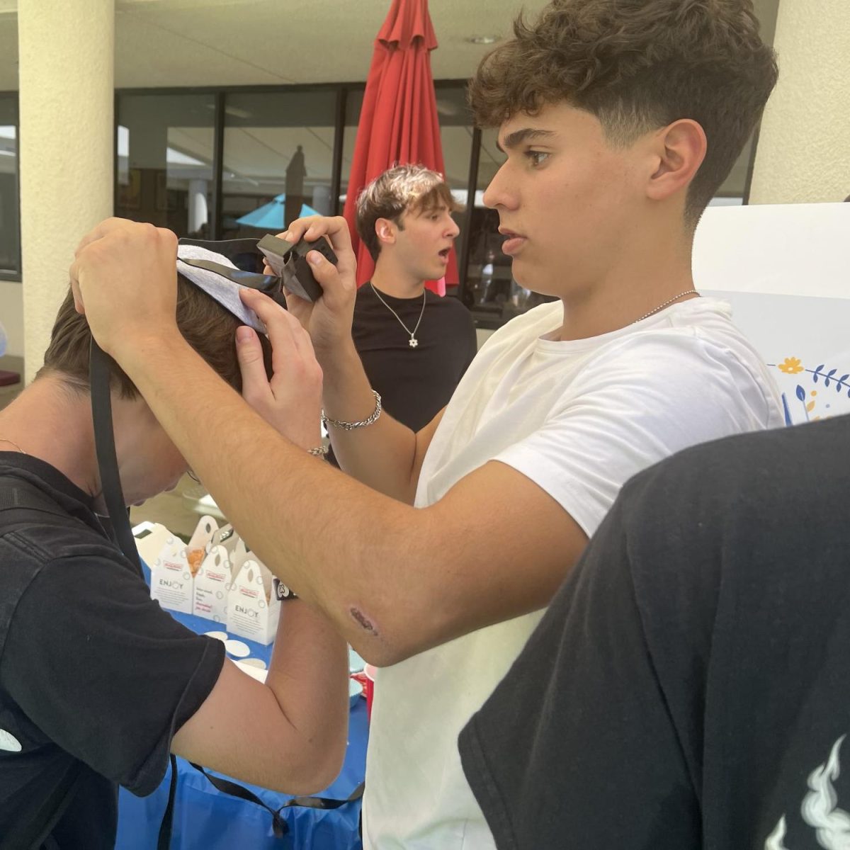 Gabriel F. ('25) wraps g someone in Tefilin for the Torah Time Club run by Tohar L. ('25) at the  Sept. 25, 2024, dTHS Club Fair.