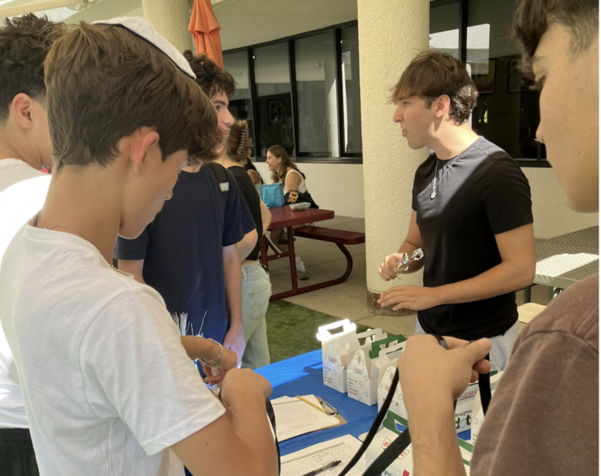 Sammy M. ('28) wrapping teffilin at a club booth at the dTHS Club Fair on 25 Sept. 2024.