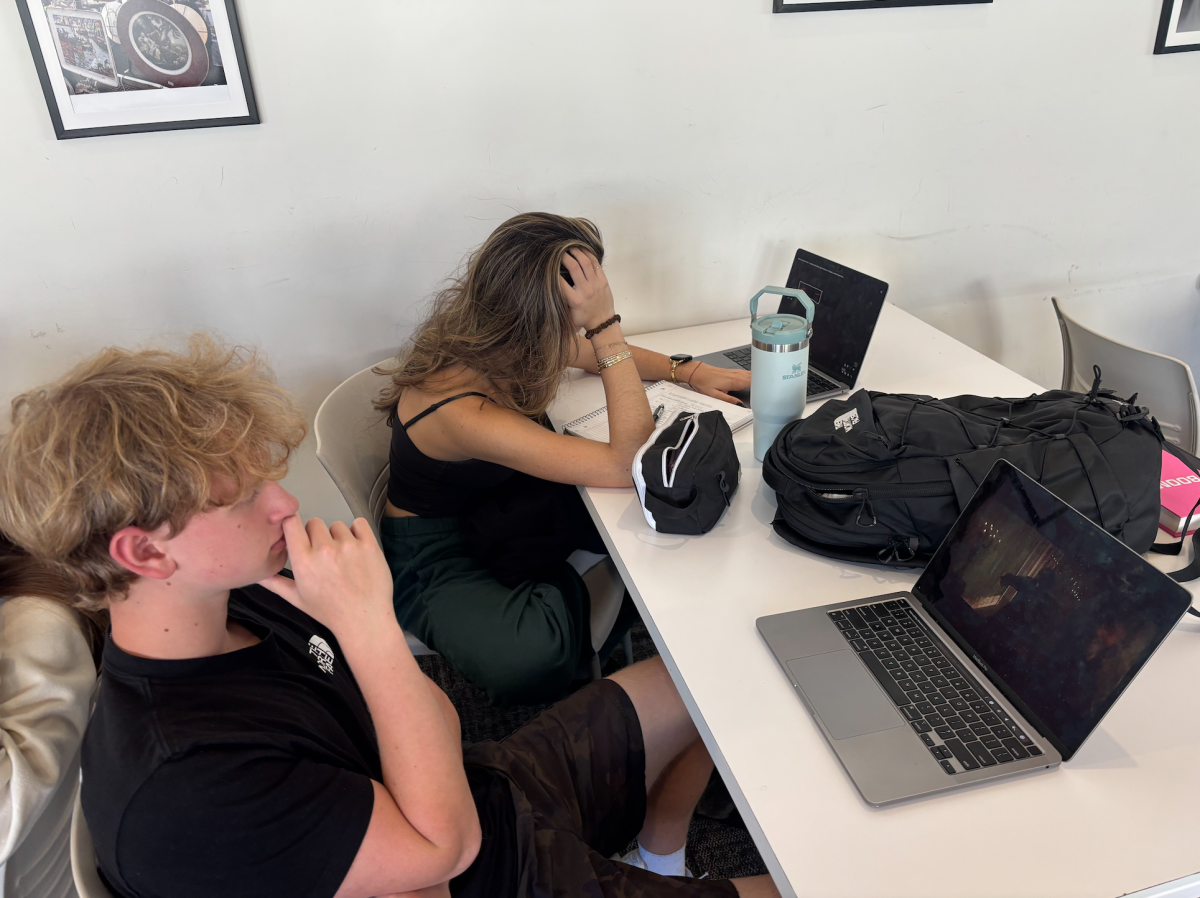 Two students in free period, one studying for math test, one watching a movie.