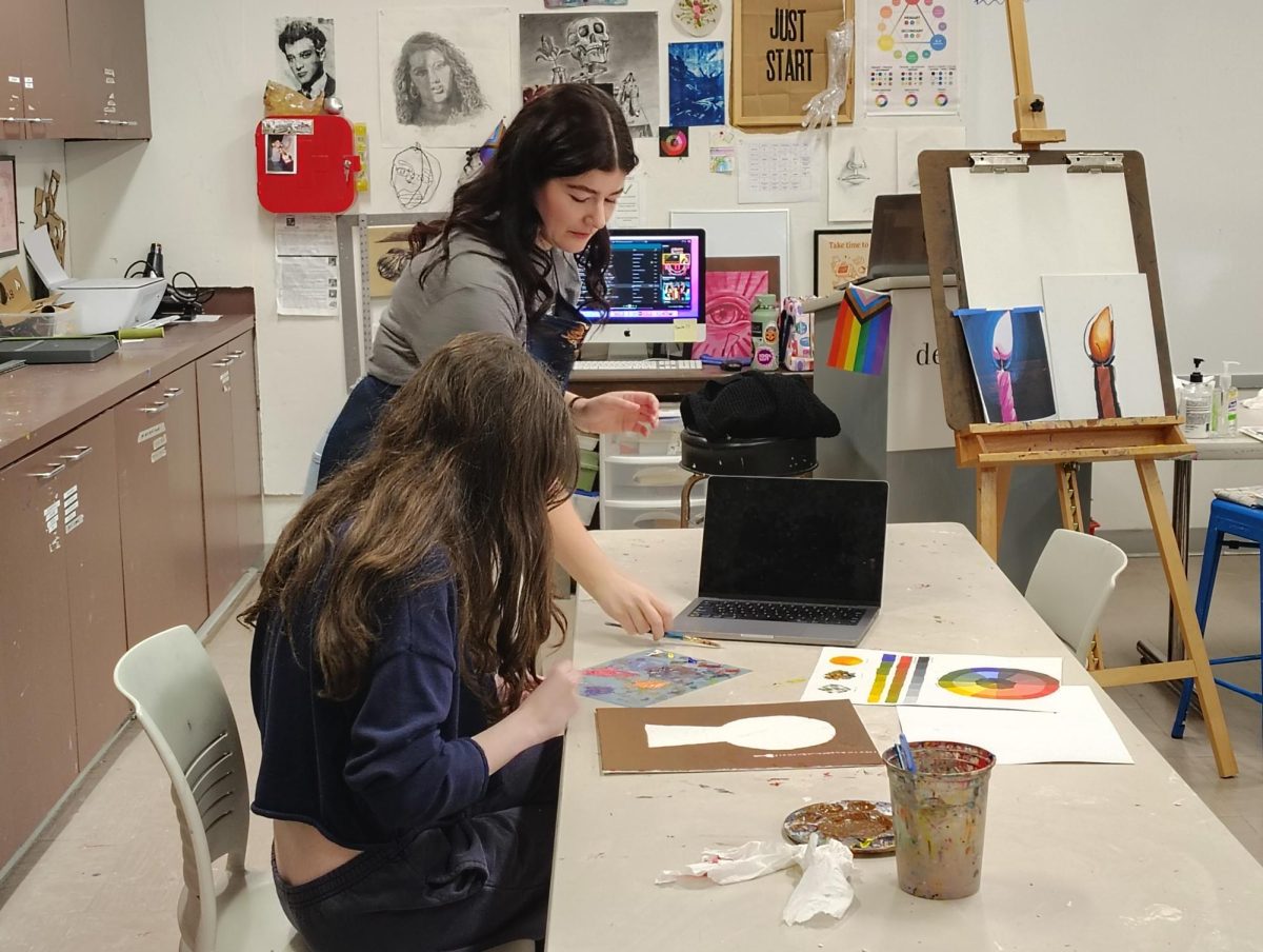 Mrs. Foster helping a student touch up her artwork.